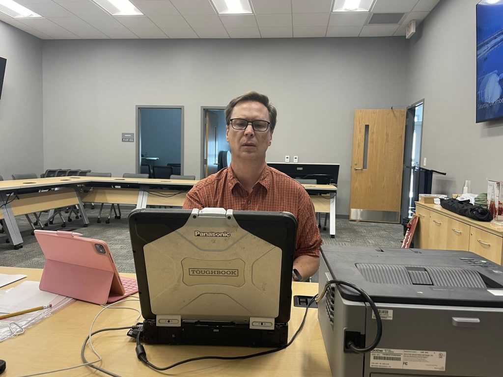 Mike Litty at a computer with printer and iPad, finalizing a ham radio test session, December 20, 2025